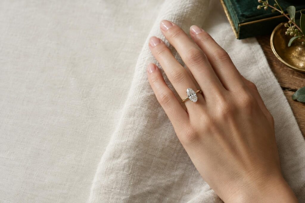 Hand wearing a gold ring with an elongated oval diamond that lengthens the finger