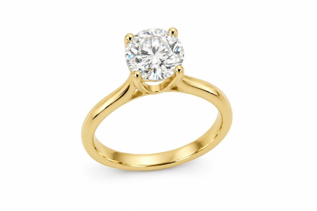 Round diamond ring held by four slim gold prongs, seen from a three-quarter angle on white